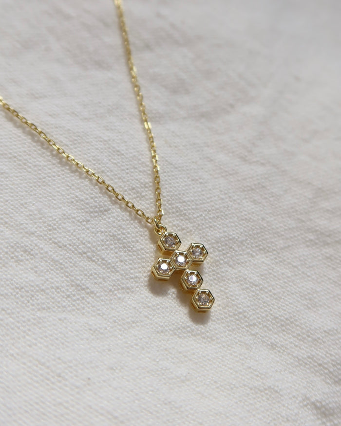 Gold-plated necklace with a cubic zirconia cross pendant on a woman's neck. Greek cross necklace, jewelry made in Greece