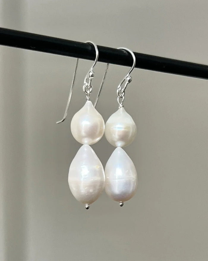 The ANN LIGHTFOOT - DOUBLE DROPLET FRESHWATER PEARL EARRINGS feature teardrop-shaped white pearls on sterling silver hooks, shown against a plain white background.