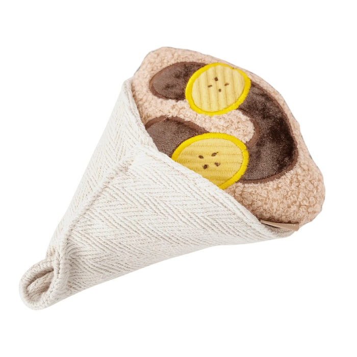 Introduce your pup to playful treat-hiding fun with the LAMBWOLF COLLECTIVE - CREPE DOG TOY by LAMBWOLF COLLECTIVE, a plush, squeaky crepe dog toy featuring brown and yellow circles that look like banana slices and chocolate sauce, all wrapped in a textured white fabric cone.