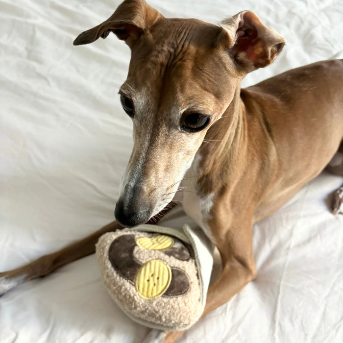 Introduce your pup to playful treat-hiding fun with the LAMBWOLF COLLECTIVE - CREPE DOG TOY by LAMBWOLF COLLECTIVE, a plush, squeaky crepe dog toy featuring brown and yellow circles that look like banana slices and chocolate sauce, all wrapped in a textured white fabric cone.