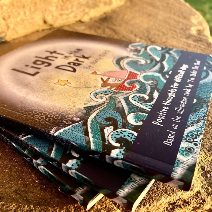 Card deck titled 'Light & Dark' with decorative cover on a textured surface