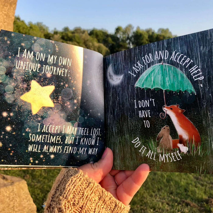 Open book with motivational quotes held by a hand outdoors.
