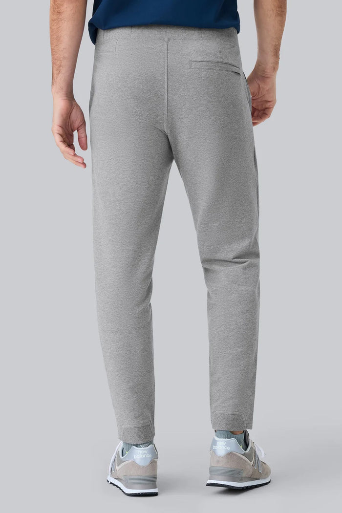 Close-up of a person wearing MACK WELDON Ace Sweatpants in True Navy Bird’s Eye with a tailored fit, drawstring waist, and pockets—one hand in the front pocket—paired with a dark blue shirt.